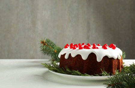 Beautifully decorated Christmas cake and fir branches on white table. Space for text