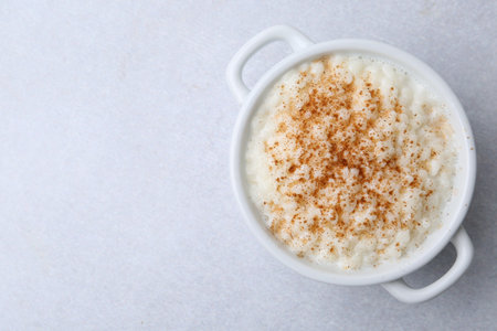 Delicious rice pudding with cinnamon on light table, top view. Space for textの写真素材
