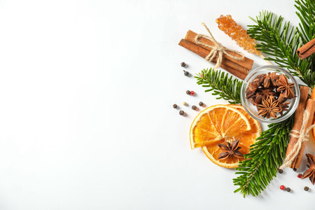 Different spices, dried orange slices and fir tree branches on white table, flat lay with space for text. Christmas seasonの写真素材