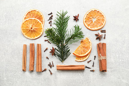 Different spices, dried orange slices and fir tree branches on light gray table, flat lay. Christmas...