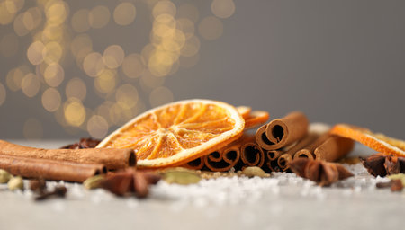 Different spices and dried orange slices on light gray table, closeup. Christmas season