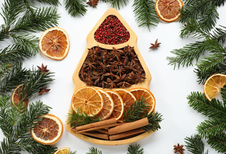 Different spices, dried orange slices and fir tree branches on white table, flat lay. Christmas seasonの写真素材