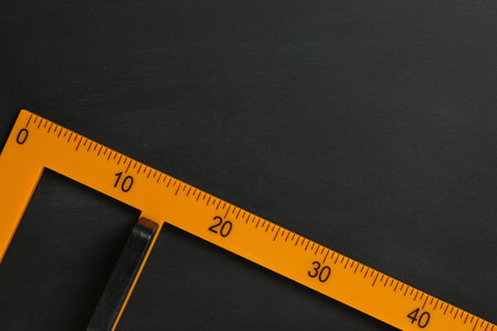 Triangle ruler on black chalkboard, top view. Space for textの写真素材