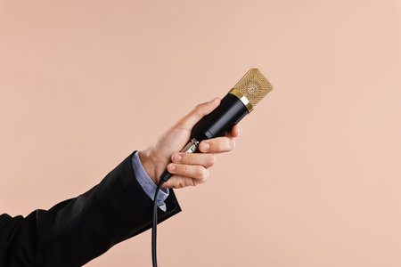 Man with microphone on beige background, closeupの写真素材