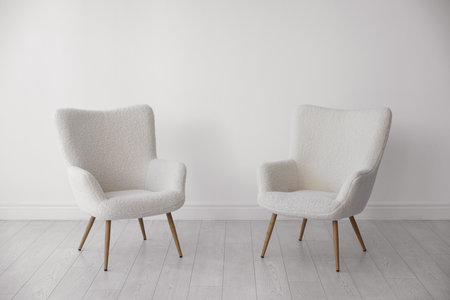 Stylish soft armchairs near white wall indoorsの写真素材