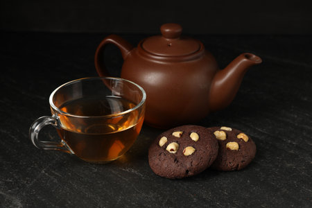 Tasty chocolate cookies with hazelnuts and tea on black tableの写真素材
