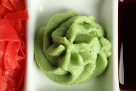 Hot wasabi paste, soy sauce and ginger on plate, top view