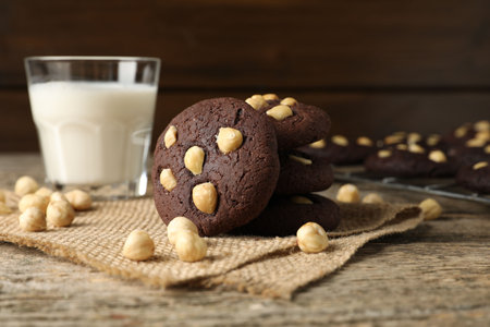 Tasty chocolate cookies with hazelnuts and milk on wooden table, closeupの写真素材