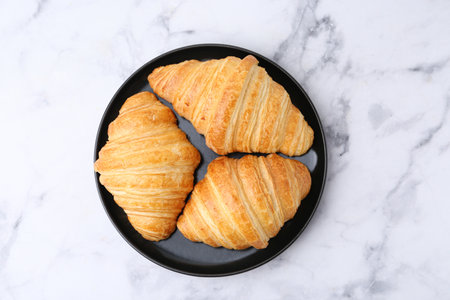 Tasty fresh croissants on white marble table, top view. Puff pastryの写真素材