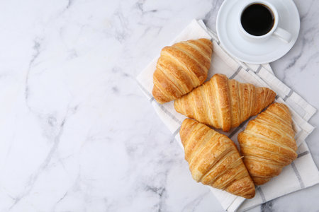 Tasty fresh croissants and cup of coffee on white marble table, flat lay. Space for textの写真素材