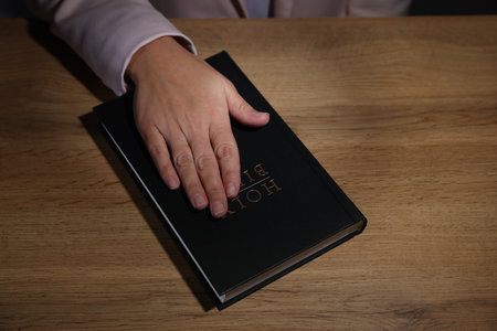 Woman taking oath with her hand on Bible at wooden table, above viewの写真素材