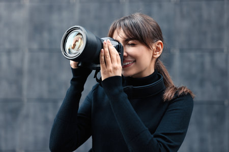 Professional photographer taking picture with camera near gray wall outdoors