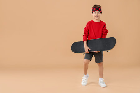 Person holding a skateboard against beige background, space for textの写真素材