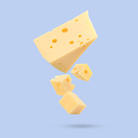 Piece of fresh cheese falling on light blue backgroundの写真素材