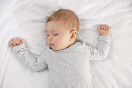 Cute little baby sleeping on bed at home, top view