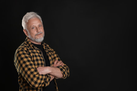 Portrait of senior man on black background, space for text