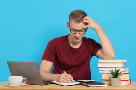 Student preparing for exam at table against light blue background
