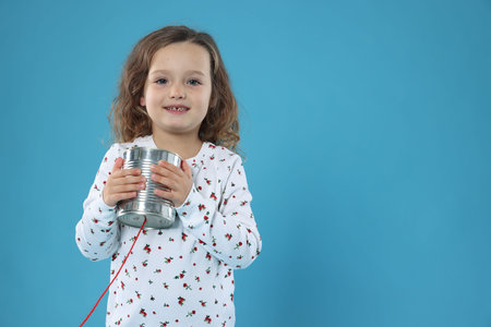 Using tin can telephone on blue background. Space for text