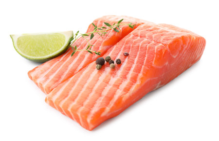 Pieces of fresh salmon, peppercorns, thyme and lime isolated on whiteの写真素材
