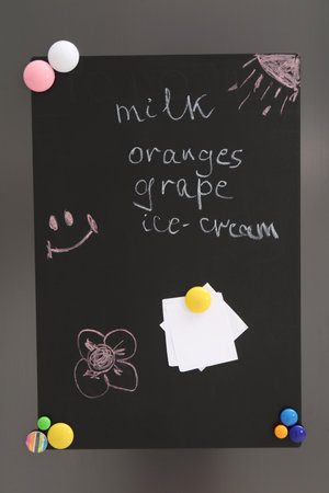 Magnetic board with shopping list and notes on refrigerator in kitchenの写真素材