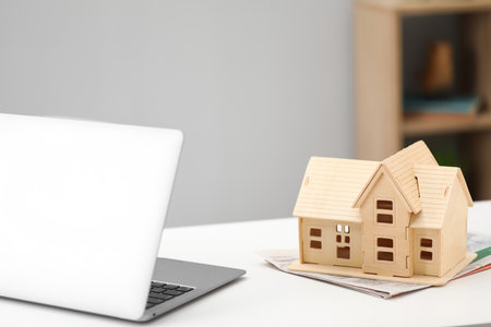 House hunting. Papers, laptop and house figure on white tableの写真素材