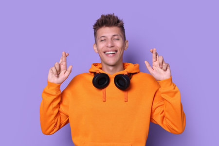 Excited young student crossing fingers on violet background.の写真素材