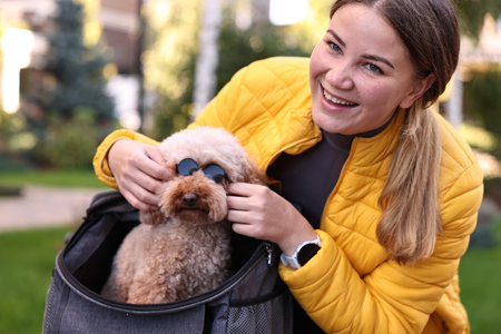Woman with cute Toy Poodle dog in sunglasses outdoors
