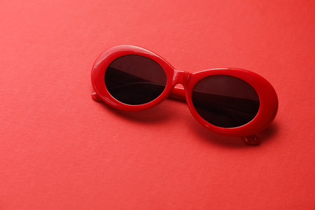 Stylish sunglasses on red background. Elegant accessoryの写真素材