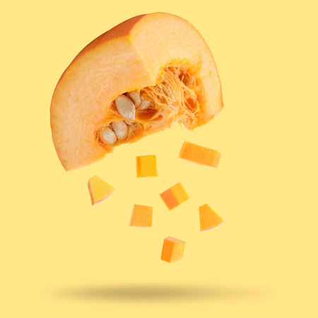 Pieces of fresh raw pumpkin falling on beige backgroundの写真素材