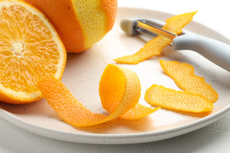Fresh orange peel, fruit and peeler on light table, closeupの写真素材