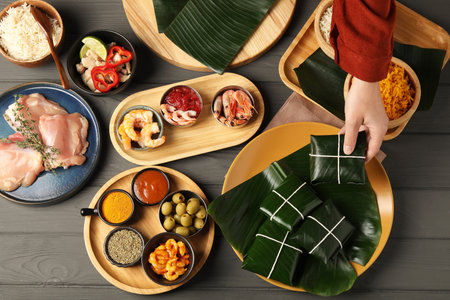 Woman taking folded banana leaf with food at wooden table with products, top viewの写真素材