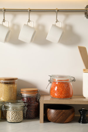 Different types of cereals and legumes in containers on light marble table in kitchenの写真素材