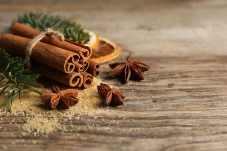 Different spices, dried orange slices and fir tree branches on wooden table, closeup with space for...