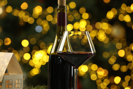 Bottle and glass of red wine against blurred Christmas lights, closeup. Bokeh effectの写真素材