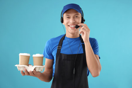 Fast-food worker with paper cups on light blue background