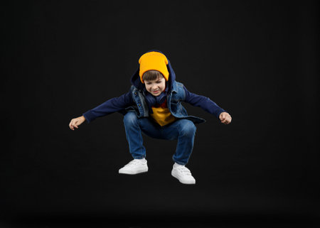 Happy little boy jumping on black background