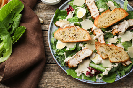 Tasty Caesar salad with chicken on wooden table, flat layの写真素材