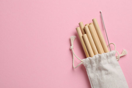 Bamboo drinking straws and cleaning brush in bag on pink background, top view. Space for textの写真素材