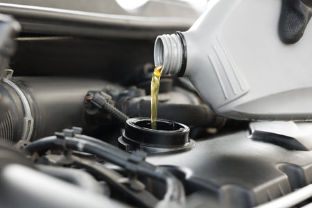 Man pouring motor oil into car engine, closeupの写真素材