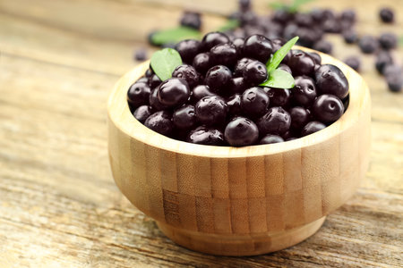 Ripe acai berries and leaves in bowl on table, closeupの写真素材