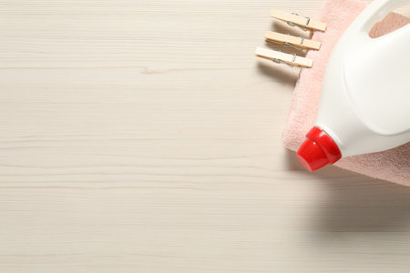 Bottle with laundry detergent, clean towel and clothespins on wooden background, top view. Space for textの写真素材
