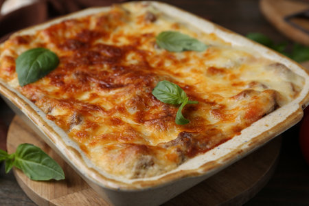 Delicious cooked lasagna in baking dish and basil on table, closeupの写真素材