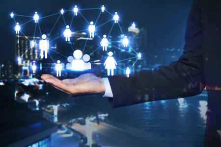 Human resource. Businessman holding virtual scheme with people figures against night cityscape, closeupの写真素材