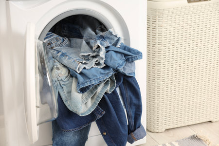 Washing machine with dirty jeans and other denim clothes indoorsの写真素材