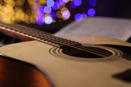 Guitar against blurred lights, closeup. Bokeh effect
