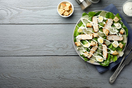 Delicious Caesar salad with chicken served on gray wooden table, flat lay. Space for textの写真素材