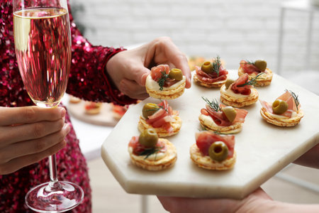 Woman taking tasty canape from waiter with board indoors, closeupの写真素材
