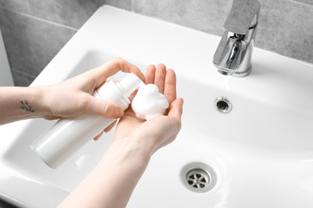 Woman washing hands with cleansing foam near sink in bathroom, closeupの写真素材