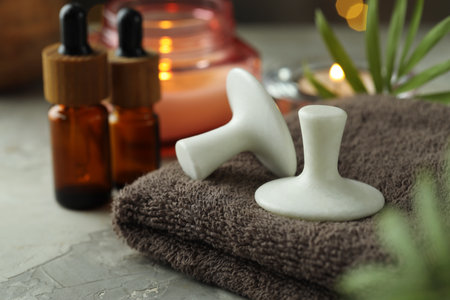 Spa stones, towel, candle and green leaves on gray table, closeupの写真素材