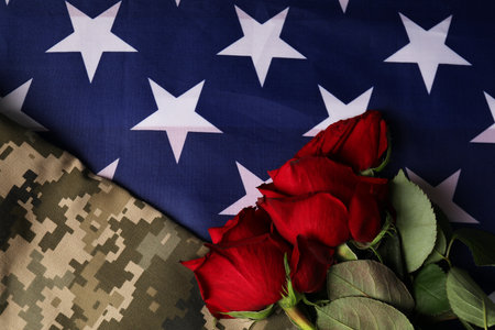 Veterans day. Rose flowers and military uniform on American flag, flat layの写真素材